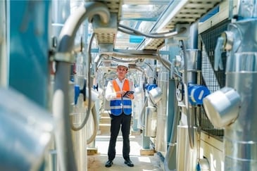 reliability engineer standing amongst pumps with tablet