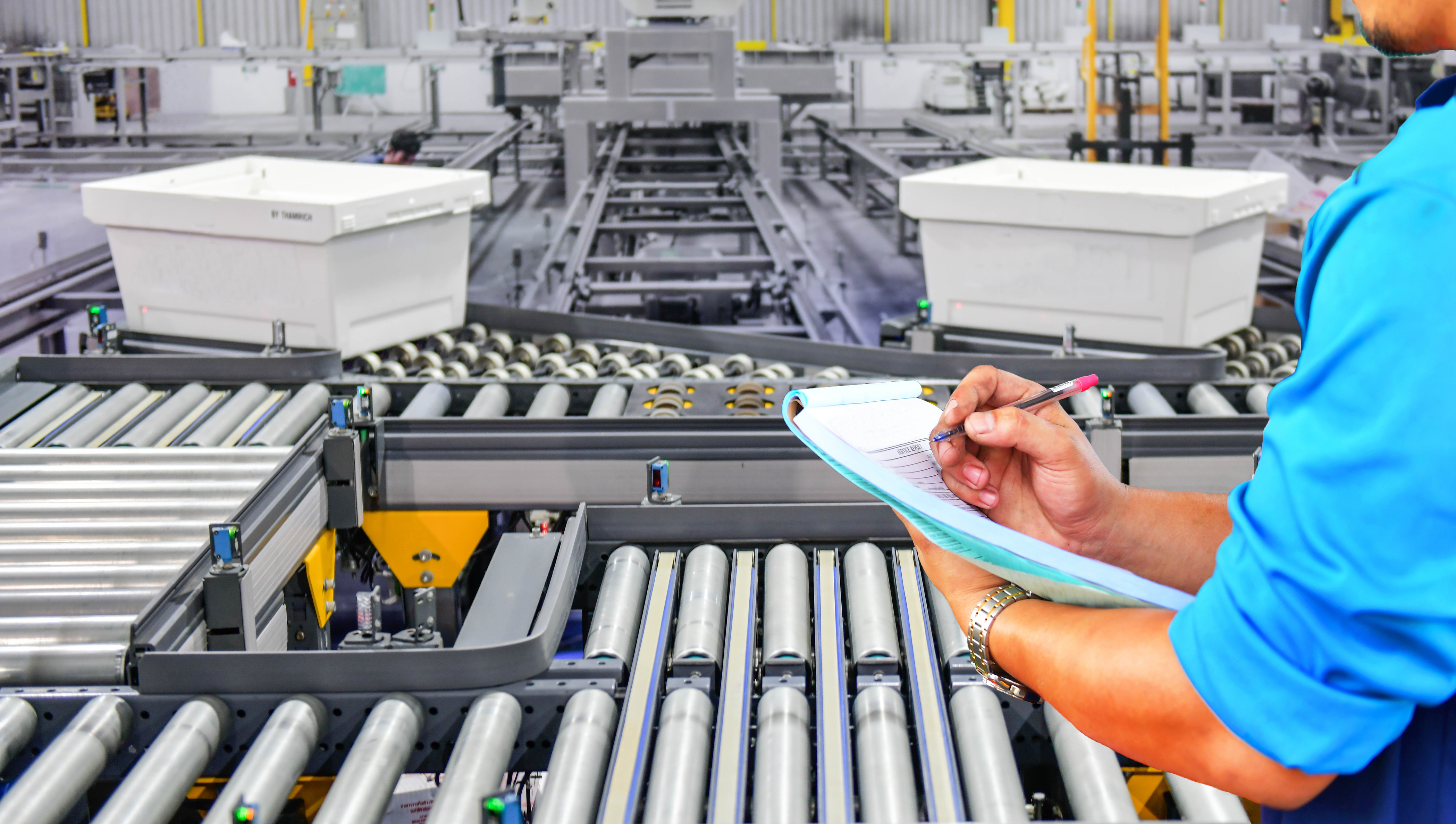 Manager engineer checking plastics boxes on conveyor belt in distribution warehouse